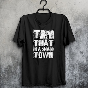 May include: Black t-shirt with white text that reads "TRY THAT IN A SMALL TOWN".