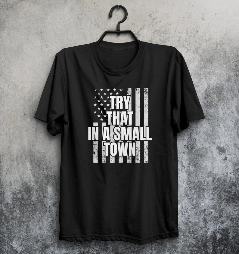 May include: Black t-shirt with a distressed American flag design and the text "TRY THAT IN A SMALL TOWN" in white.