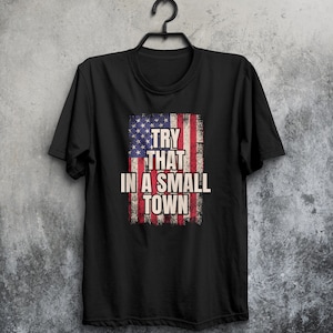 May include: Black t-shirt with a distressed American flag design and the text "Try that in a small town".