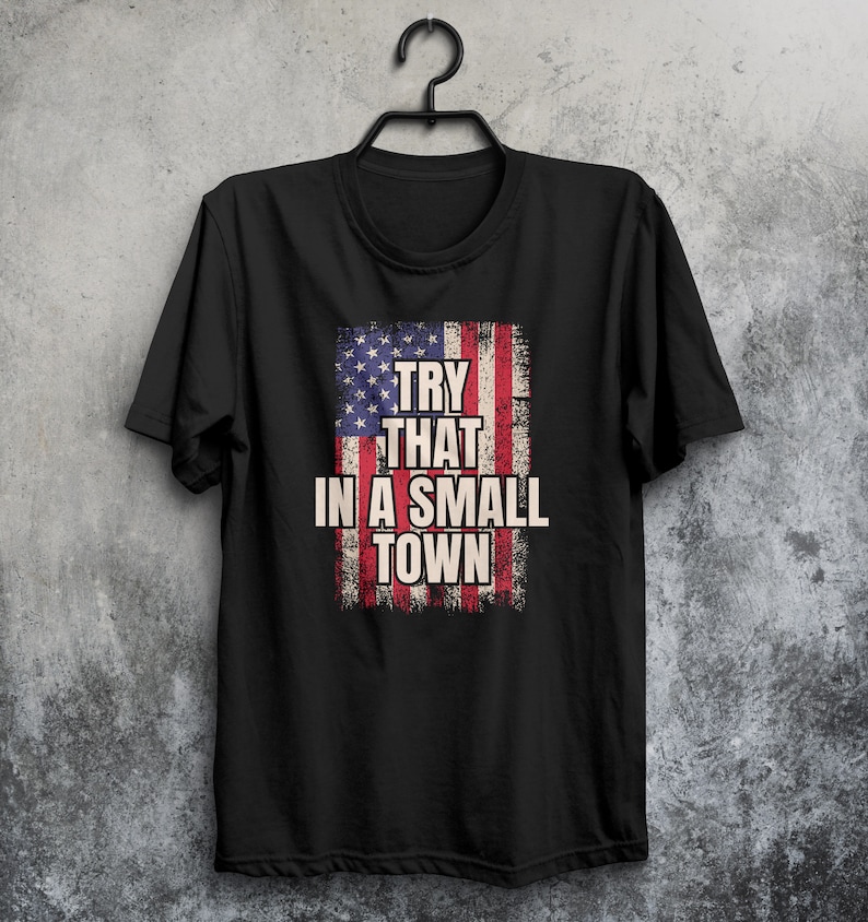 May include: Black t-shirt with a distressed American flag design and the text "Try that in a small town".