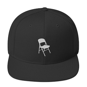 May include: Black and white embroidered folding chair design on a black fitted baseball cap.