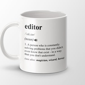 Könnte beinhalten: Eine weiße Keramiktasse mit einer schwarz-weißen Definition des Wortes "Editor" darauf gedruckt. Die Definition lautet: "Eine Person, die ständig Probleme löst, von denen man nicht einmal wusste, dass sie existieren - auf eine Weise, die man nicht versteht. (siehe auch: Zauberer, Zauberer, Held)"
