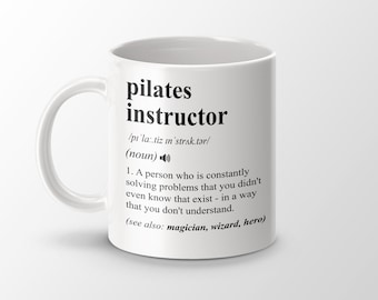 May include: White ceramic mug with a black definition of "pilates instructor" printed on it. The definition reads: "A person who is constantly solving problems that you didn't even know that exist - in a way that you don't understand. (see also: magician, wizard, hero)"