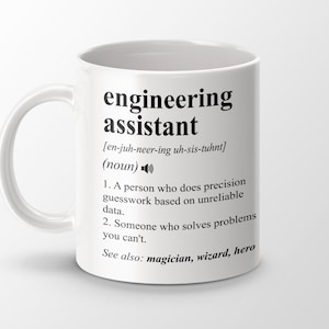 Pode incluir: Caneca de cerâmica branca com o texto "engineering assistant" e sua definição. A definição inclui a pronúncia, uma descrição da função e termos relacionados como "magician, wizard, hero".
