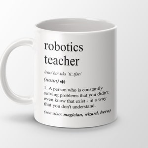 Op de afbeelding: Een witte keramische mok met een zwart ontwerp waarop "robotics teacher" staat, met een definitie van het woord. De definitie luidt: /roo'ba:.tıks 'ti:.tfər/ (zelfstandig naamwoord) 1. Iemand die voortdurend problemen oplost waarvan je niet eens wist dat ze bestonden - op een manier die je niet begrijpt. (zie ook: tovenaar, tovenaar, held)