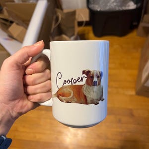 May include: White ceramic mug featuring a brown and white dog illustration with the name "Cooper" written in cursive.