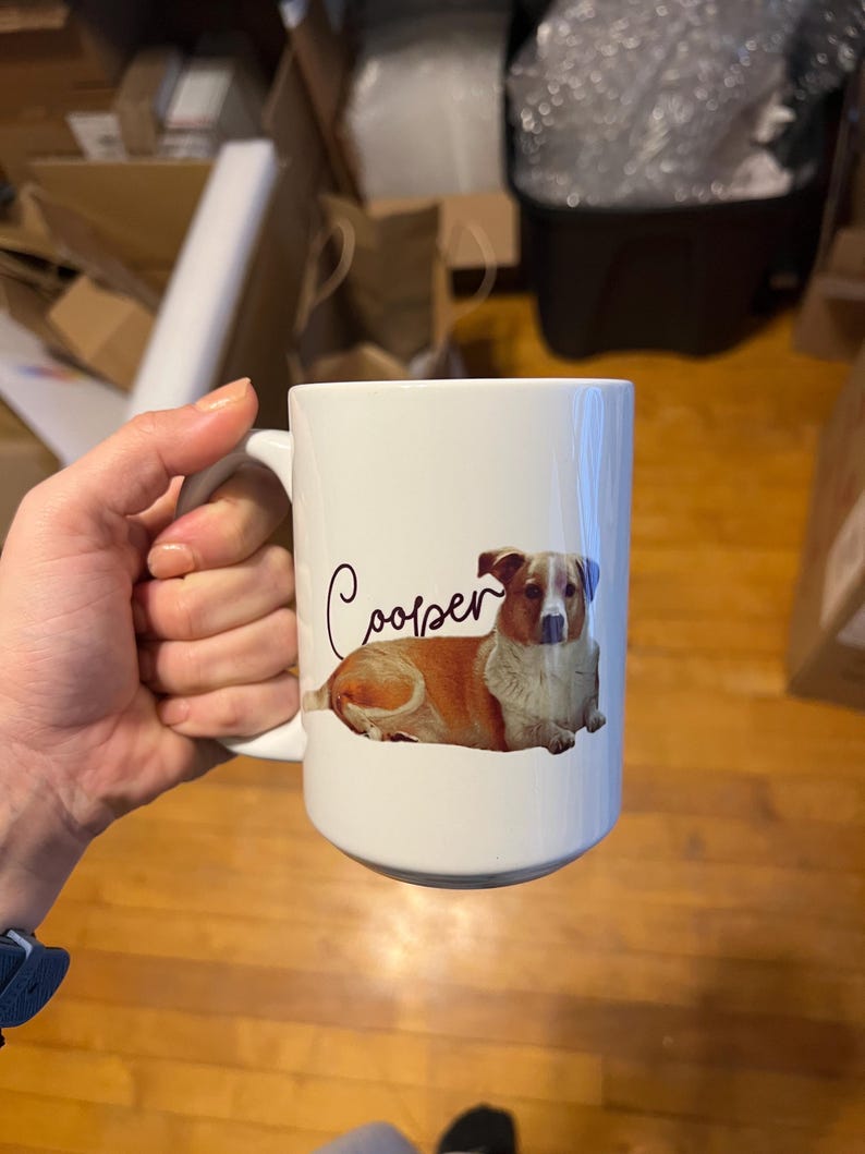May include: White ceramic mug featuring a brown and white dog illustration with the name "Cooper" written in cursive.