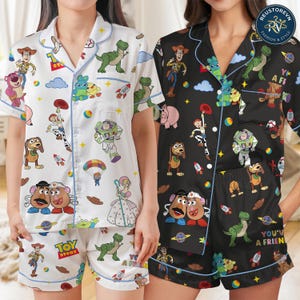 Peut inclure: Deux ensembles de pyjamas à manches courtes boutonnés avec des imprimés de personnages Toy Story. Un ensemble est blanc avec un passepoil bleu, et l'autre est noir avec un passepoil bleu. Les deux présentent Woody, Buzz l'Éclair et Rex.