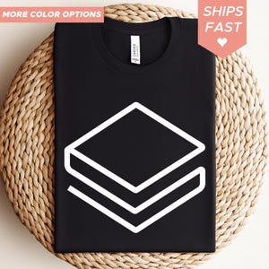 May include: Black t-shirt with a white geometric design. The shirt has a crew neck and is made of a soft material. The words "MORE COLOR OPTIONS" and "SHIPS FAST" are visible in the image.
