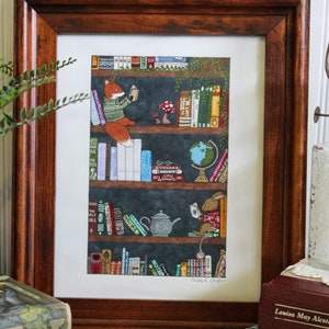 May include: A framed illustration of a bookshelf filled with books, a globe, a teapot, and a mushroom. A fox and a rabbit are sitting on the shelves reading books. The text at the bottom of the illustration reads "Cheers to good books".