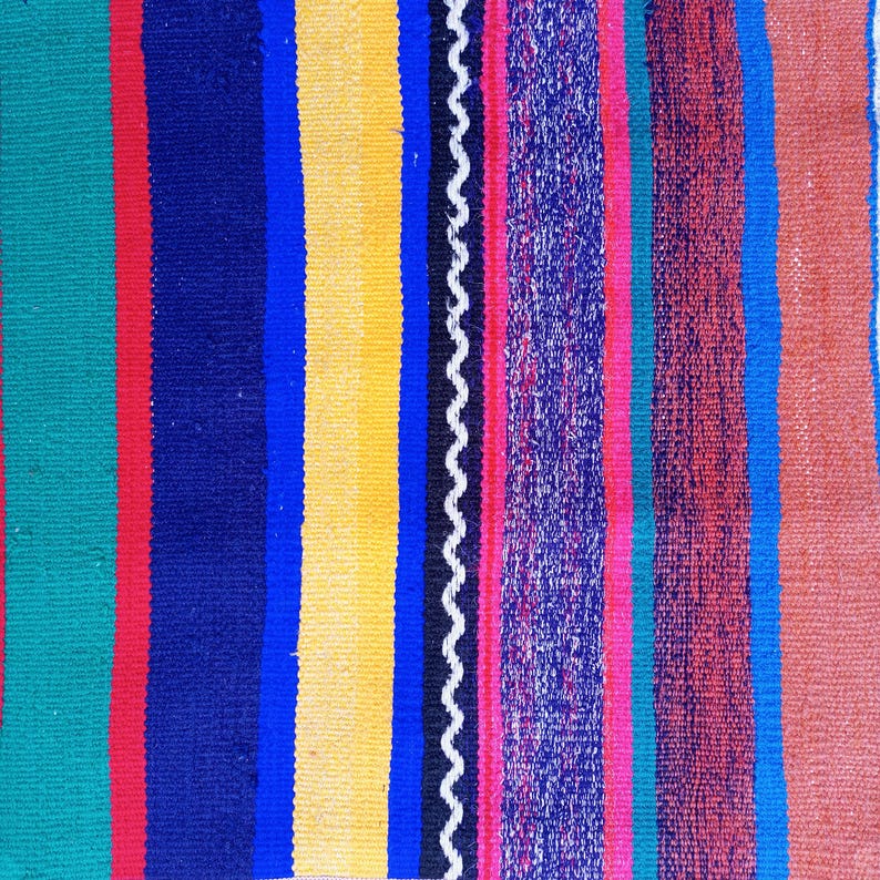 K&ouml;nnte beinhalten: Ein bunter gestreifter Teppich mit einer Vielzahl von Farben, darunter Gr&uuml;n, Rot, Blau, Gelb, Schwarz, Wei&szlig;, Rosa und Braun.