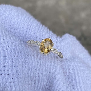 Peut inclure: Une bague en argent avec une grande topaze ovale et de petites pierres précieuses claires serties dans une bande délicate.