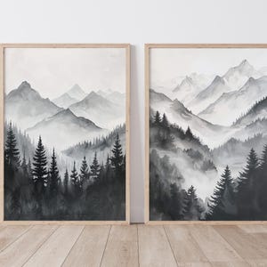 May include: Two framed black and white watercolour paintings of a mountain range with a forest in the foreground. The mountains are misty and the trees are silhouetted against the sky.