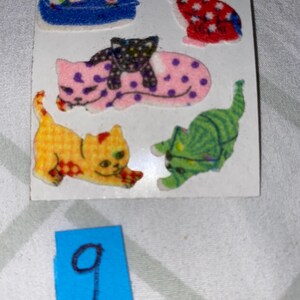 May include: A sheet of colorful cat stickers. The stickers feature a variety of cats in different poses, including a cat sleeping, a cat sitting, and a cat with a kitten on its back. The stickers are perfect for adding a touch of whimsy to any project.