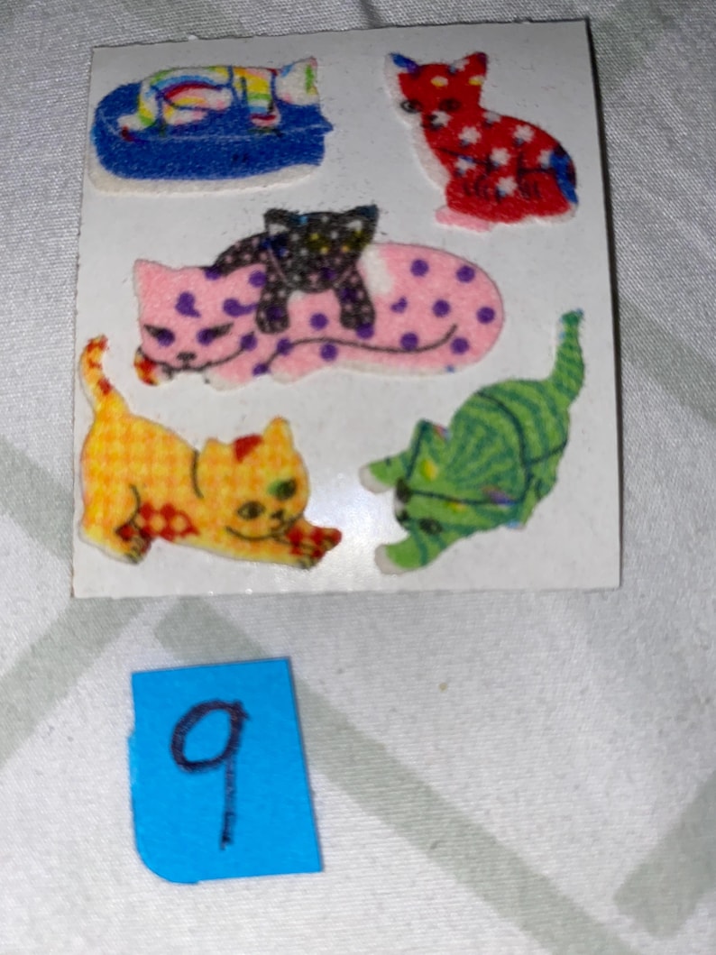 May include: A sheet of colorful cat stickers. The stickers feature a variety of cats in different poses, including a cat sleeping, a cat sitting, and a cat with a kitten on its back. The stickers are perfect for adding a touch of whimsy to any project.