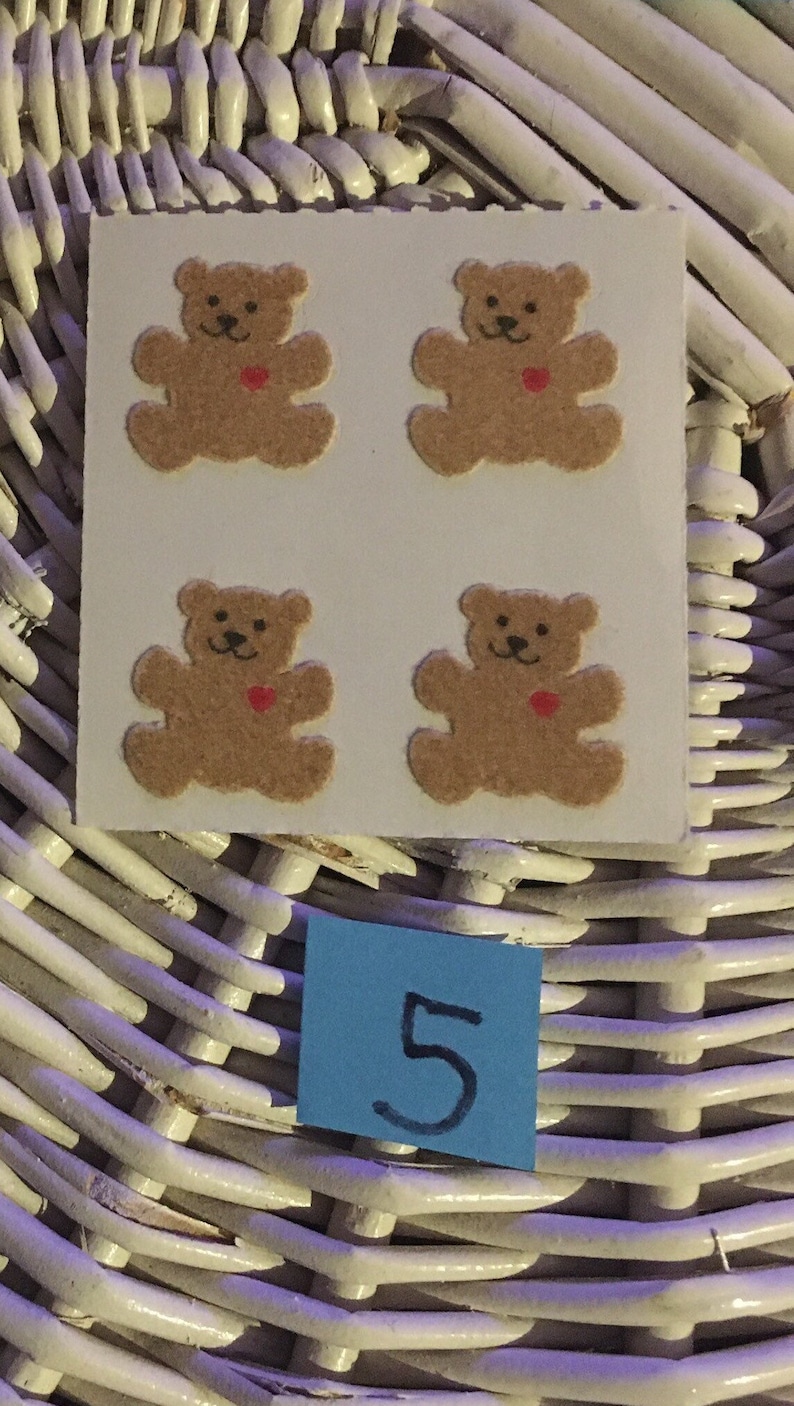 May include: Four brown teddy bear stickers with red hearts on a white background. The stickers are arranged in a 2x2 grid. The number 5 is written on a blue sticky note.