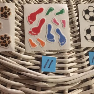 May include: Three sheets of stickers with different designs. The first sheet has five paw prints with a brown and orange leopard print. The second sheet has nine colorful footprints. The third sheet has four black and white soccer balls. The sheets are labeled with the numbers 10, 11, and 12.
