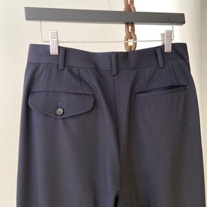 K&ouml;nnte beinhalten: Schwarze, ma&szlig;geschneiderte Hose mit einem einzigen Knopf an der Ges&auml;&szlig;tasche.
