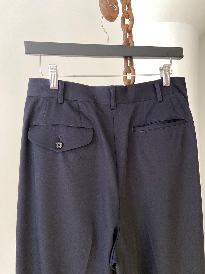 K&ouml;nnte beinhalten: Schwarze, ma&szlig;geschneiderte Hose mit einem einzigen Knopf an der Ges&auml;&szlig;tasche.
