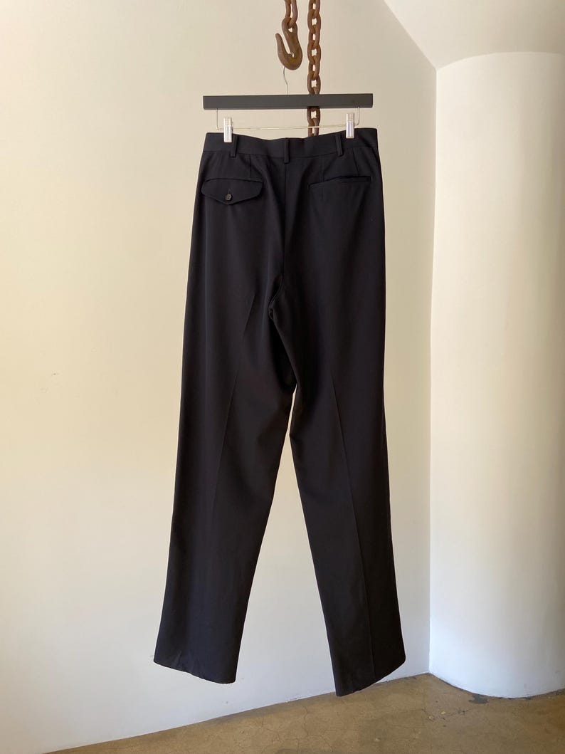 K&ouml;nnte beinhalten: Schwarze, ma&szlig;geschneiderte Hose mit einer einzigen Ges&auml;&szlig;tasche und einem Knopfverschluss.