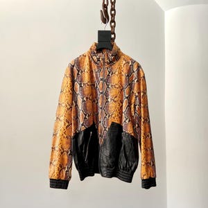 May include: A brown and black snakeskin patterned jacket with a black leather zipper and black leather accents on the front and sleeves.