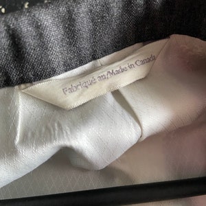 May include: A white label with black text that reads "Fabriqu&eacute; au/Made in Canada" attached to a black and white patterned fabric.