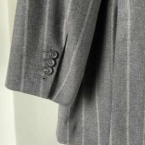 May include: A gray striped blazer with a single button on the cuff.