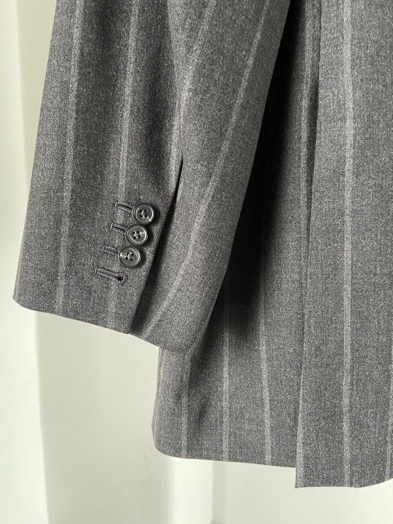 May include: A gray striped blazer with a single button on the cuff.
