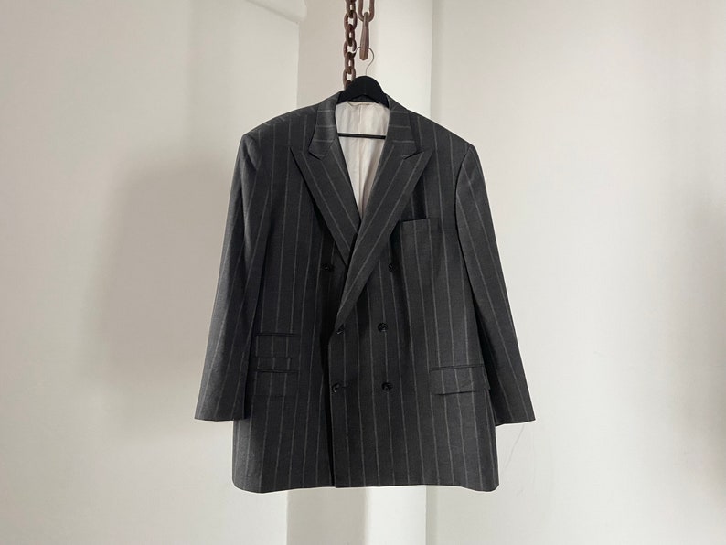May include: A dark gray pinstripe double-breasted blazer with a notch lapel.