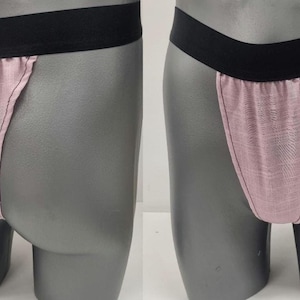 May include: A pair of pink underwear with a black waistband. The underwear has a thong style back.