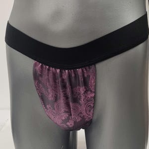 May include: Black elastic waistband with a purple and black paisley patterned fabric pouch.
