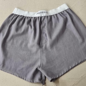 May include: Grey cotton boxer shorts with a white elastic waistband. The waistband has the text "Premium Quality" printed on it.
