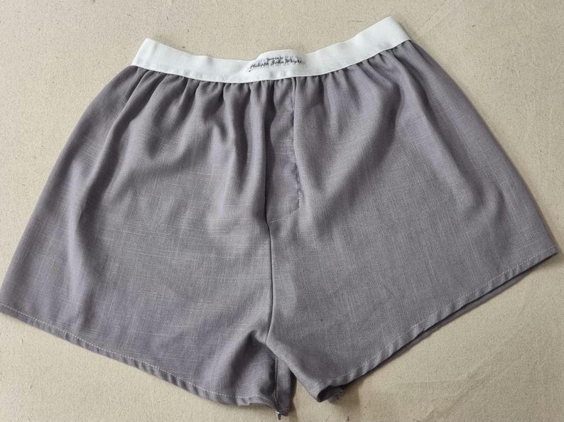 May include: Grey cotton boxer shorts with a white elastic waistband. The waistband has the text "Premium Quality" printed on it.