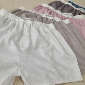 May include: Five pairs of white, beige, pink, grey, and blue cotton shorts. The shorts are made from a lightweight, breathable fabric and have a relaxed fit.