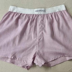 May include: A pair of light pink cotton shorts with a white elastic waistband. The waistband has the word "Zimmerli" printed on it.