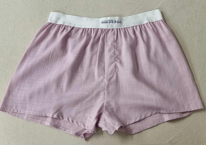 May include: A pair of light pink cotton shorts with a white elastic waistband. The waistband has the word "Zimmerli" printed on it.