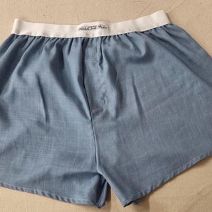 May include: A pair of blue cotton boxer shorts with a white elastic waistband.