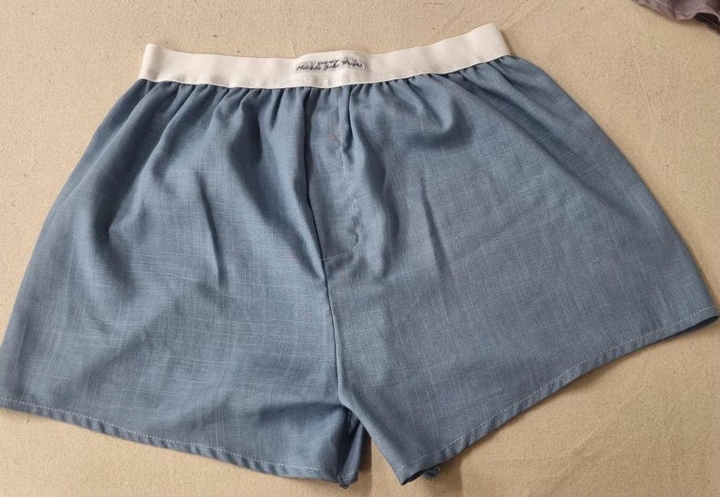 May include: A pair of blue cotton boxer shorts with a white elastic waistband.