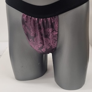 Puede incluir: Una prenda interior con estampado negro y morado con una banda elástica negra.