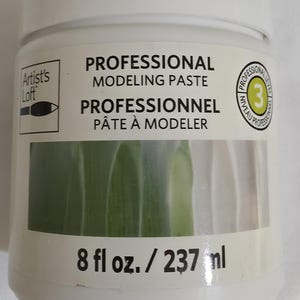 May include: A white plastic jar of Artist's Loft Professional Modeling Paste with a screw-top lid. The label features the text Professional Modeling Paste, Professionnel Pâte à Modeler, and a level 3 professional icon. It contains 8 fl oz. / 237 ml.