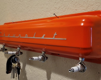 May include: Orange Chevrolet valve cover key holder with four spark plug hooks.