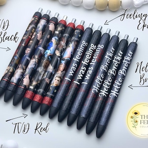 Pu&ograve; includere: Un set di dieci penne nere e rosse con glitter con varie citazioni stampate su di esse, tra cui "I was feeling", "Hello Brother" e "Hello Brother". Le penne sono disposte in fila su una superficie bianca. Il testo "TVD Black" e "TVD Red" &egrave; scritto sui lati sinistro e destro dell'immagine, rispettivamente. Il testo "Feeling Epic" &egrave; scritto nella parte superiore dell'immagine, con una freccia che punta alle penne. Il testo "Hello Brother" &egrave; scritto nella parte inferiore dell'immagine, con una freccia che punta alle penne.