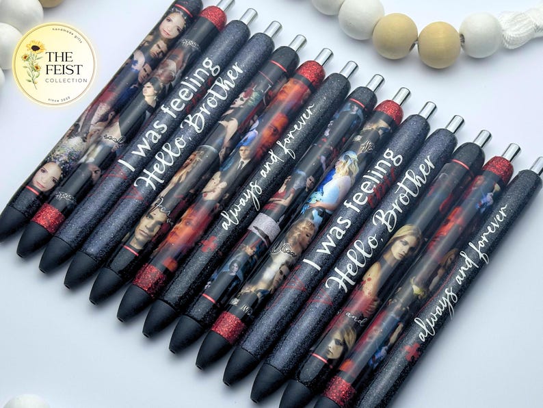 Pu&ograve; includere: Un set di dieci penne nere con glitter e accenti di glitter rosso. Ogni penna ha un'immagine e un testo diversi. Il testo sulle penne include "I was feeling", "Hello Brother" e "always and forever".