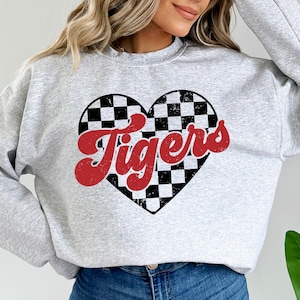 May include: Gray sweatshirt with a red checkered heart and the word "Tigers" in red script.