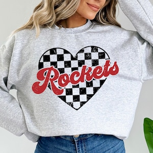 May include: Gray sweatshirt with a red and black checkered heart design and the word "Rockets" in red lettering.