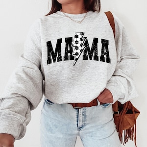 May include: Grey sweatshirt with a black and white lightning bolt graphic and the word "MAMA" in black letters.