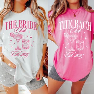 Könnte beinhalten: Zwei T-Shirts, eines weiß und eines pink, mit dem Text "THE BRIDE Club" und "THE BACH Club". Jedes Shirt hat eine Cocktailgrafik und den Text "Est. 2025". Die Shirts sind lässig und für einen Junggesellinnenabschied geeignet.