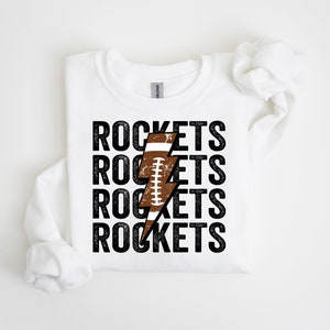 May include: White sweatshirt with a black graphic of a football-shaped lightning bolt and the word "ROCKETS" repeated four times.