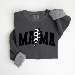 May include: A charcoal grey sweatshirt with a black and white lightning bolt graphic and the word "MAMA" in black block letters.