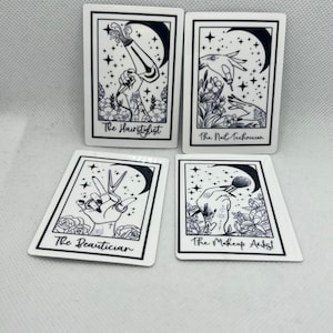 May include: Four black and white illustrations of hands holding tools associated with beauty services. The illustrations are set against a background of stars and a crescent moon. The text below each illustration reads "The Hairstylist", "The Nail Technician", "The Beautician", and "The Makeup Artist".